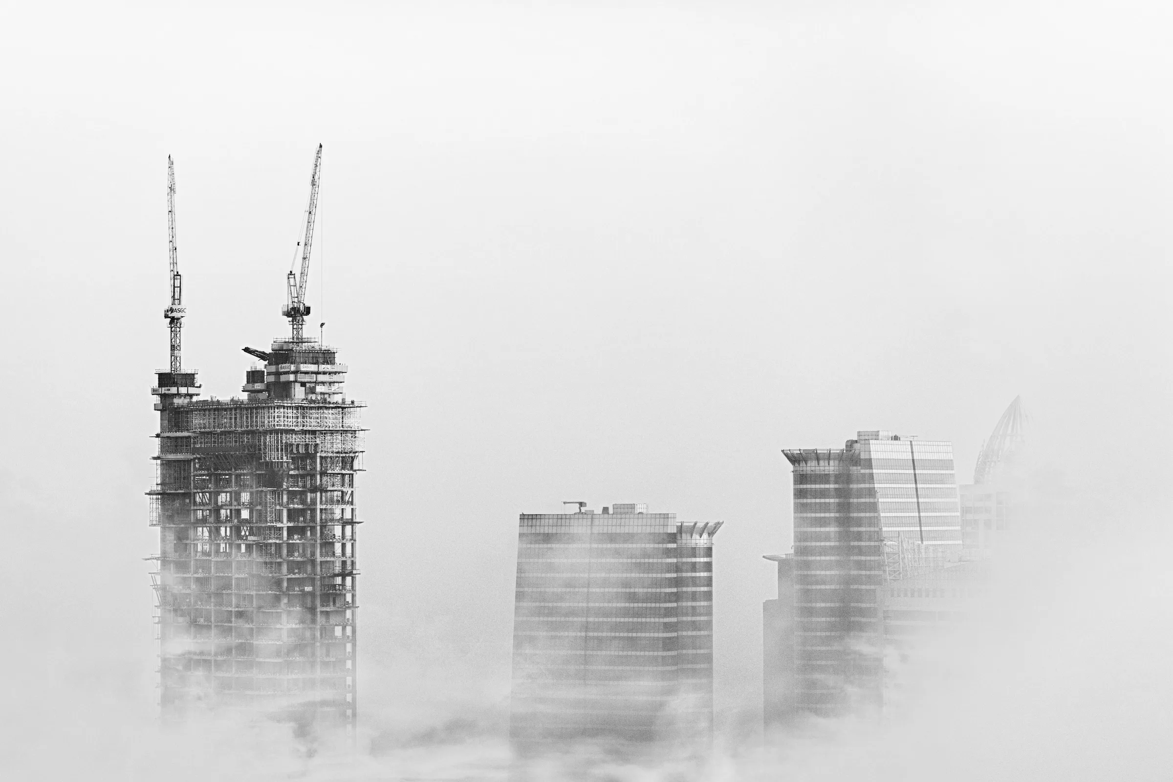 Towers under construction rising through the morning fog